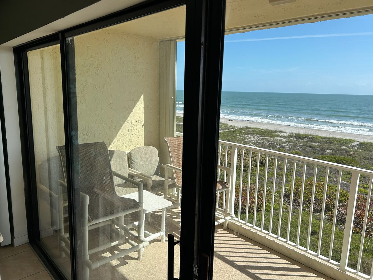 Florida resort walkway lined with guest-room sliding glass doors at sunset