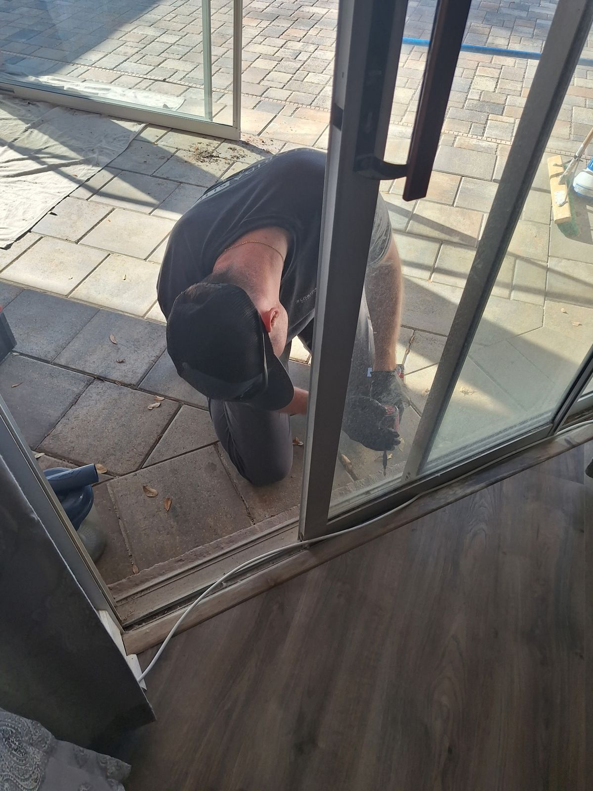 Technician servicing a sliding glass door on a paver patio — sliding glass door services in Winter Garden, Florida